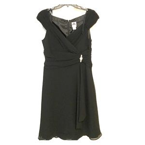 Black wrap style dress with brooch accent